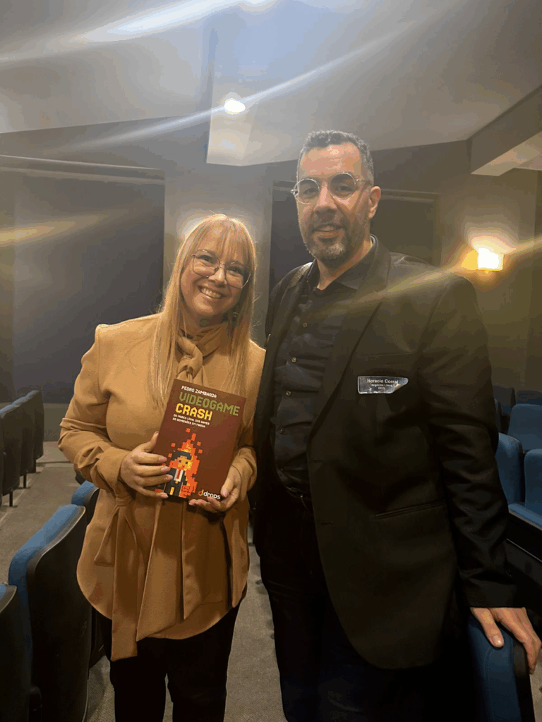 Horácio Corral, da Tacet Books e Critical Hit Books, entregando uma cópia do livro Video Game Crash, de autoria do jornalista Pedro Zambarda, à secretária de cultura do estado de SP, Marília Marton